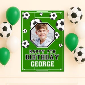 May include: A green and white soccer-themed birthday banner with the text "HAPPY 7TH BIRTHDAY GEORGE" and a photo of a young boy. The banner is surrounded by green, white, and black soccer ball balloons.