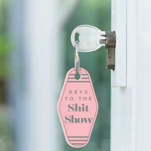 May include: Pink motel key chain with the text "Keys to the Shit Show" in gray lettering.
