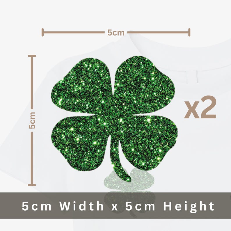 May include: Two green glitter shamrock appliques, each 5 cm wide and 5 cm high, are displayed on a white background. The image includes the text "x2" indicating the quantity. The shamrocks are a festive decoration.