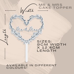 May include: A white cake topper with a heart-shaped wreath design and the text "Mr & Mrs" in the center. The topper is 9 inches wide and 12.4 inches long.  Available in different colors.