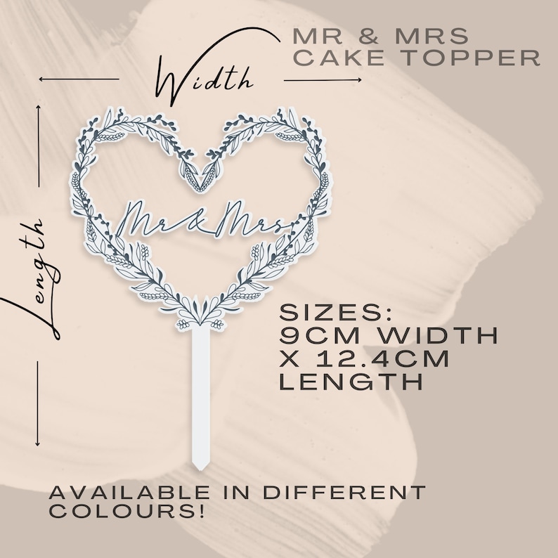 May include: A white cake topper with a heart-shaped wreath design and the text "Mr & Mrs" in the center. The topper is 9 inches wide and 12.4 inches long.  Available in different colors.