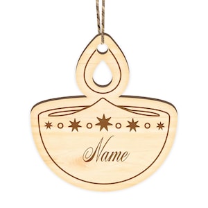 K&ouml;nnte beinhalten: Ein Holz-Anh&auml;nger in Form einer Diya, einer traditionellen indischen &Ouml;llampe, mit einer Schnur zum Aufh&auml;ngen. Der Anh&auml;nger ist mit Sternen verziert und das Wort "Name" ist auf der Vorderseite eingraviert.