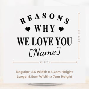 May include: A white card with black text that reads "REASONS WHY WE LOVE YOU [Name]". The card includes two black hearts. Measurements are provided: Regular 6.5" width x 5.4cm height, Large 8.5cm width x 7cm height.