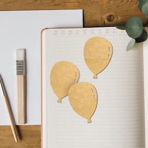 May include: Three brown paper balloon cutouts on a lined notebook page. The balloons are arranged in a cluster, with the largest balloon at the top and the two smaller balloons below.