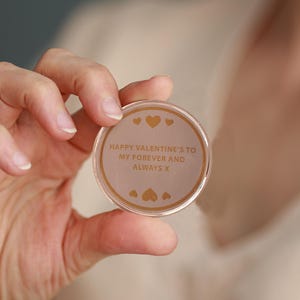 May include: A round, clear plastic token with a gold inscription that reads "Happy Valentine's to my forever and always x". The token has small gold hearts around the inscription.