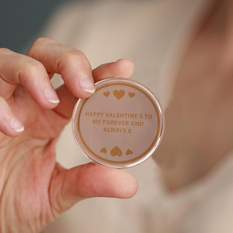 May include: A round, clear plastic token with a gold inscription that reads "Happy Valentine's to my forever and always x". The token has small gold hearts around the inscription.