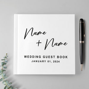 May include: White wedding guest book with the text "Name + Name" and "Wedding Guest Book January 01, 2024" printed on the front cover.