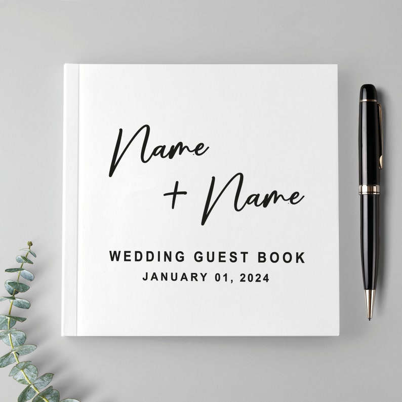 May include: White wedding guest book with the text "Name + Name" and "Wedding Guest Book January 01, 2024" printed on the front cover.