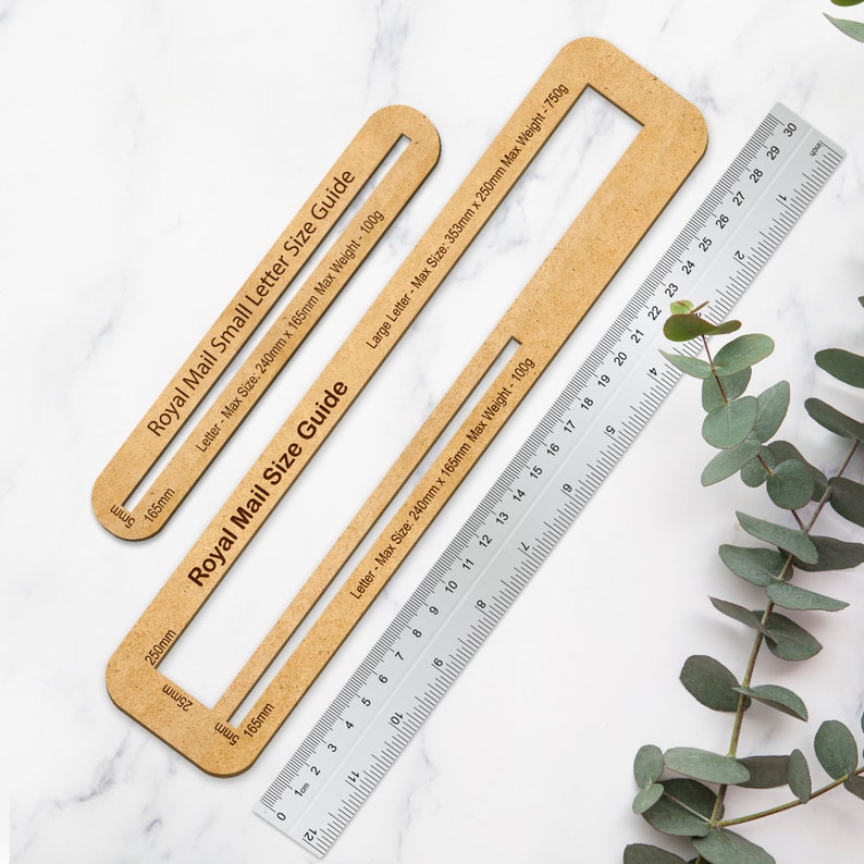 May include: Two wooden guides for measuring the size of envelopes for Royal Mail postage. The guides are labeled with the maximum size and weight for both small and large letters. A ruler is included for reference.