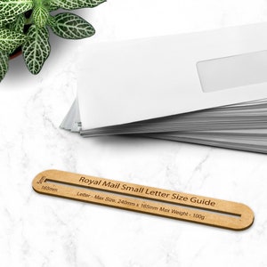 May include: A wooden ruler with a brown background and red text. The ruler is labeled "Royal Mail Small Letter Size Guide" and shows the maximum size for a letter is 9.45 inches by 6.5 inches and the maximum weight is 3.5 ounces.
