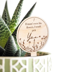 May include: A round wooden sign with a brown floral design and the text "If mum's were like flowers, I would pick You" with a heart.