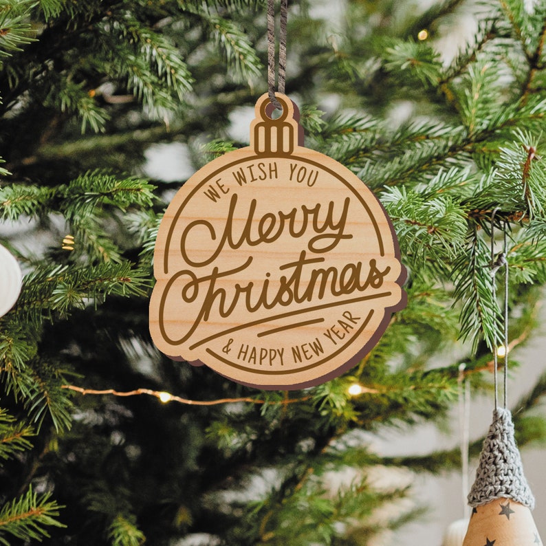 May include: A wooden Christmas ornament shaped like a bauble with the text "We wish you Merry Christmas & Happy New Year" engraved on it.
