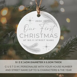 Op de afbeelding: Witte ronde kerstbal met de tekst "Our First Christmas at No. 11 Street Name" en het jaar 2024. De kerstbal is 6 cm in diameter en 0,3 cm dik.