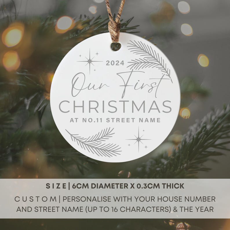 Op de afbeelding: Witte ronde kerstbal met de tekst "Our First Christmas at No. 11 Street Name" en het jaar 2024. De kerstbal is 6 cm in diameter en 0,3 cm dik.