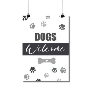 May include: A white poster with the words "DOGS Welcome" in gray and white. The poster has paw prints scattered across the background and a bone graphic. The poster is hanging from two black clips.
