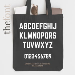 May include: Black tote bag with white uppercase letters and numbers. The bag displays the alphabet and numbers 0-9 in a bold, sans-serif font. Text at the bottom reads "UPPERCASE ONLY. NO SPECIAL CHARACTERS."