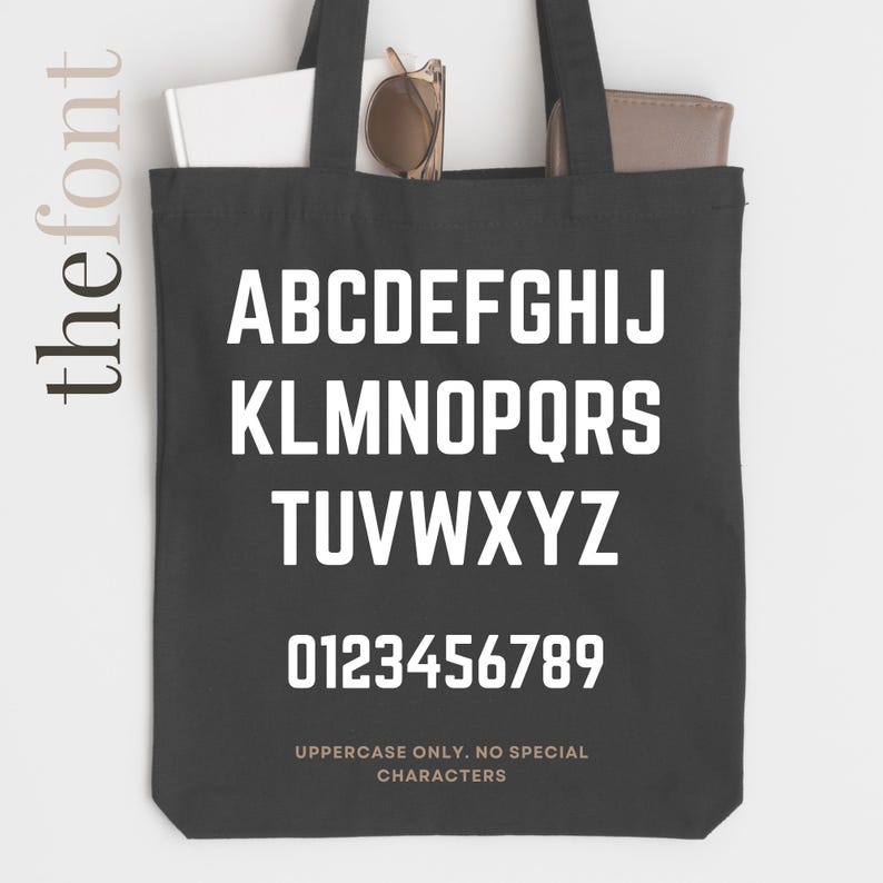 May include: Black tote bag with white uppercase letters and numbers. The bag displays the alphabet and numbers 0-9 in a bold, sans-serif font. Text at the bottom reads "UPPERCASE ONLY. NO SPECIAL CHARACTERS."