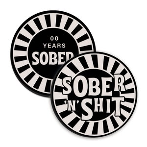 May include: Two black and white circular coasters with a white sunburst design. The top coaster says "00 Years Sober" and the bottom coaster says "Sober 'n' Shit".