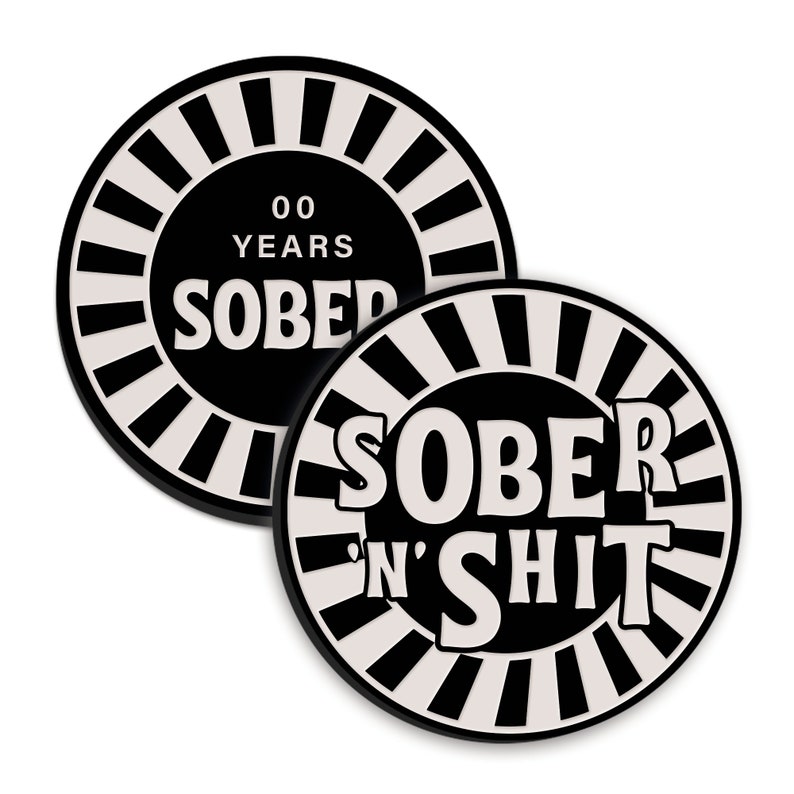 May include: Two black and white circular coasters with a white sunburst design. The top coaster says "00 Years Sober" and the bottom coaster says "Sober 'n' Shit".