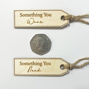 Pu&ograve; includere: Due etichette regalo in legno con un cordoncino attaccato. L'etichetta superiore dice "Something You Wear" e l'etichetta inferiore dice "Something You Need".