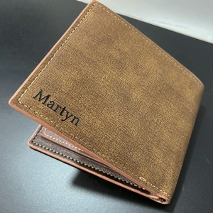 May include: A brown leather wallet with a stitched edge and the name "Martyn" embossed on the front.