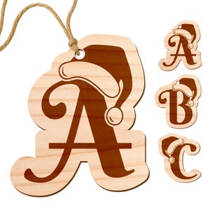 May include: Wooden Christmas ornaments in the shape of the letters A, B, and C, each adorned with a Santa hat. The letter A is larger and has a string for hanging. The ornaments are made of light-colored wood with a brown design.