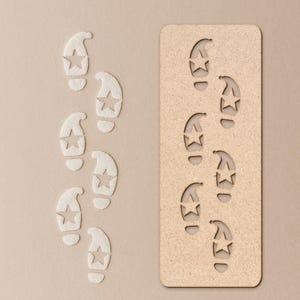 May include: A light beige background features a series of star-shaped footprints. To the left, the footprints are made of a white material. To the right, a wooden stencil displays the same footprint design.