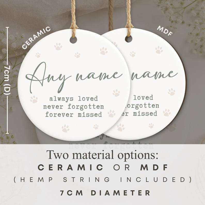 May include: Two round, white ceramic and MDF ornaments with hemp string. Each ornament has a paw print design and the words "Any name" in script. The text "always loved, never forgotten, forever missed" is also printed. The diameter is 7cm.