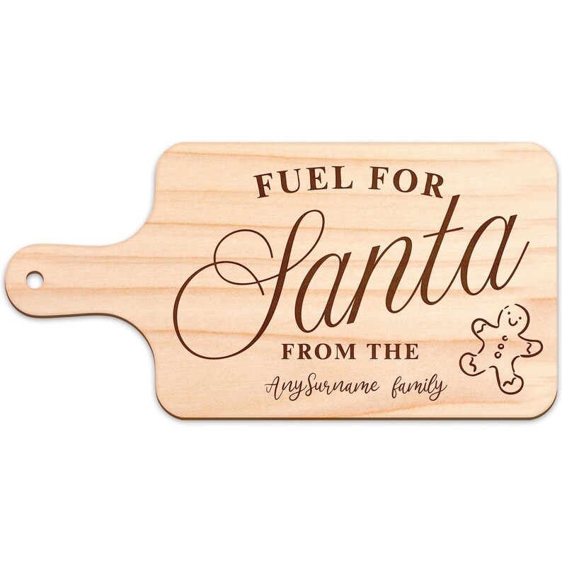 May include: A wooden cutting board with a handle, featuring the text "FUEL FOR Santa" in a decorative font. Below, it reads "FROM THE" and "AnySurname family". A gingerbread man graphic is on the right.