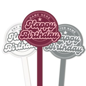 May include: Three cake toppers with the text "Happy Birthday" in a retro font. The toppers are in three different colors: burgundy, white, and gray. Each topper has a star and the text "Name Here" or "Enter Name" around the edge.
