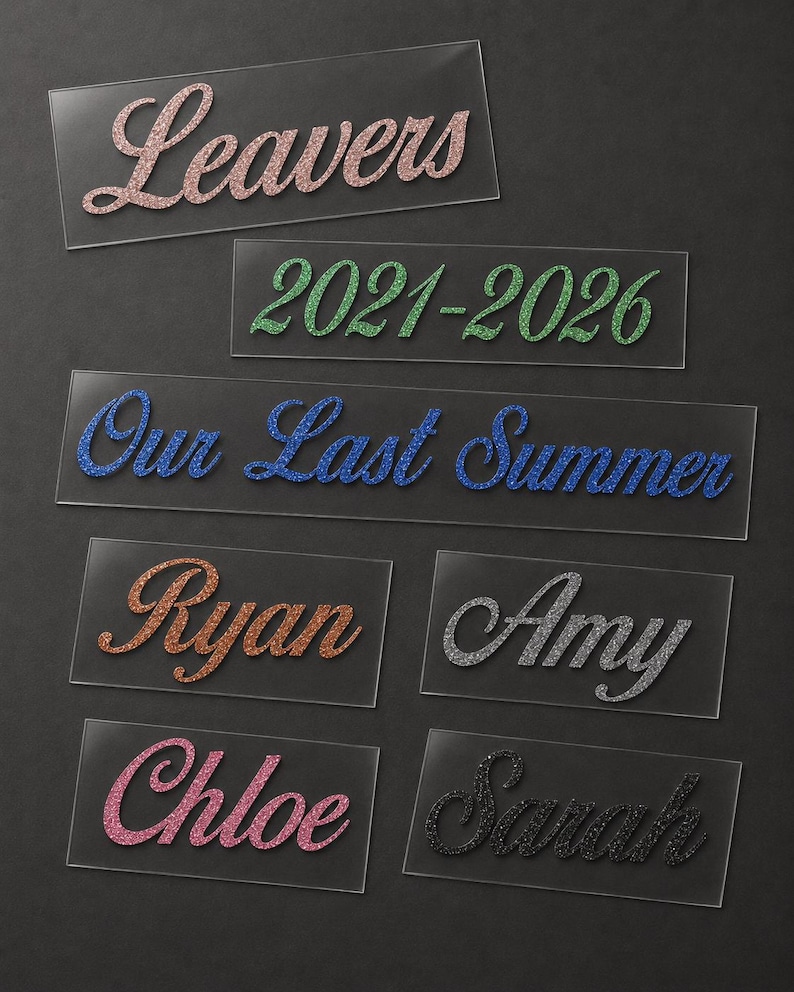 May include: A collection of clear rectangular labels with glitter text. The labels display phrases like "Leavers" and "Our Last Summer," along with names such as "Ryan" and "Amy." The text colors include pink, green, blue, orange, silver, and black.