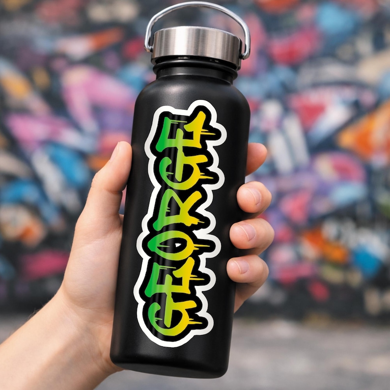 May include: Black water bottle with a silver lid, featuring a vibrant sticker with the name "GEORGE" in a graffiti-style font. The text transitions from green to yellow, outlined in white.