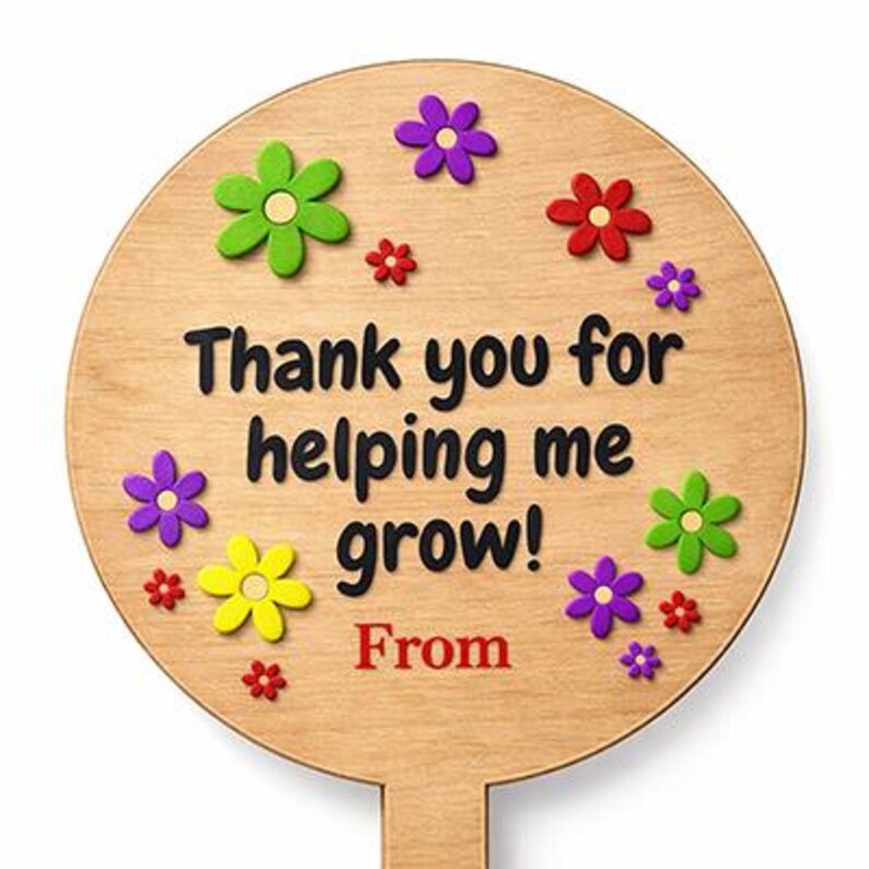 May include: A round wooden sign with the text "Thank you for helping me grow!" in black. The sign is decorated with colorful flower accents in green, purple, yellow, and red. The word "From" is in red.