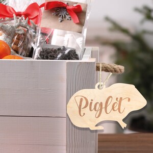 May include: A white wooden crate with a wooden piglet ornament attached to the side. The ornament is engraved with the word "Piglet".
