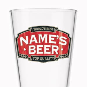 May include: A clear beer glass with a red and white label. The label reads "WORLD'S BEST NAME'S BEER TOP QUALITY" in white text with black and gold accents. The glass has a slightly tapered shape.