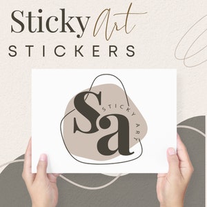 May include: A white card with the text "Sticky Art Stickers" and a logo featuring the letters "Sa" in a brown color, surrounded by a beige circle with a black outline. The logo is set against a white background.