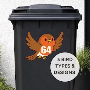 Op de afbeelding: Een zwarte vuilnisbak met een kleurrijke vogelsticker. De vogel heeft bruine vleugels, een oranje borst en het nummer 64 in het wit. Een witte cirkel eronder leest "3 BIRD TYPES & DESIGNS".