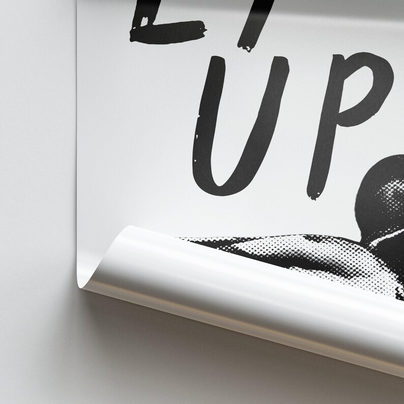 Op de afbeelding: Zwart-witte poster met de tekst "Eat Up" in vetgedrukte, handgeschreven letters. De poster toont een zwart-witte afbeelding van een persoon met zijn hoofd naar achteren gekanteld, alsof hij eet.