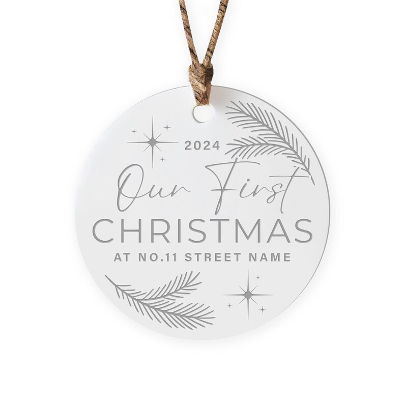 Op de afbeelding: Ronde witte kerstbal met een grijs ontwerp. De kerstbal heeft de tekst "Our First Christmas" met het jaar 2024 en "At No. 11 Street Name".