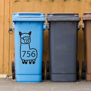 May include: Three blue, black, and brown recycling bins with a black and white alpaca sticker on the blue bin. The sticker has the number 756 on it.