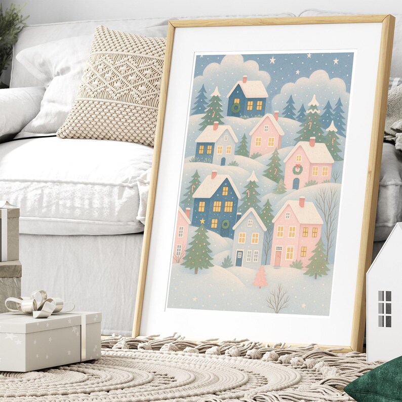 May include: A framed art print featuring a whimsical winter village scene. The illustration depicts colorful houses nestled among snow-covered hills and evergreen trees under a starry sky. The houses are painted in shades of blue, pink, and gray.