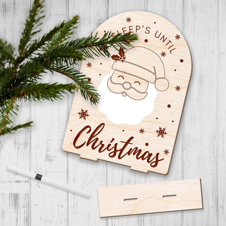 May include: A wooden sign with a cutout of Santa's face and the text "Sleep's Until Christmas". The sign is decorated with snowflakes and a holly sprig.