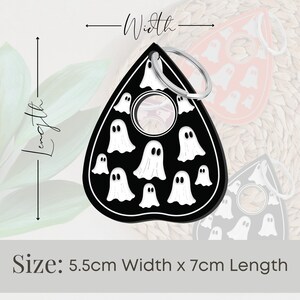 May include: Black and white ghost-shaped keychain with a silver ring. The keychain is 5.5 cm wide and 7 cm long.  Size: 5.5cm Width x 7cm Length