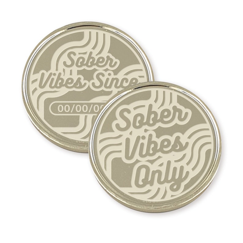 May include: Two silver-colored metal tokens with a white design. One token says "Sober Vibes Since" with a blank space for a date. The other token says "Sober Vibes Only".