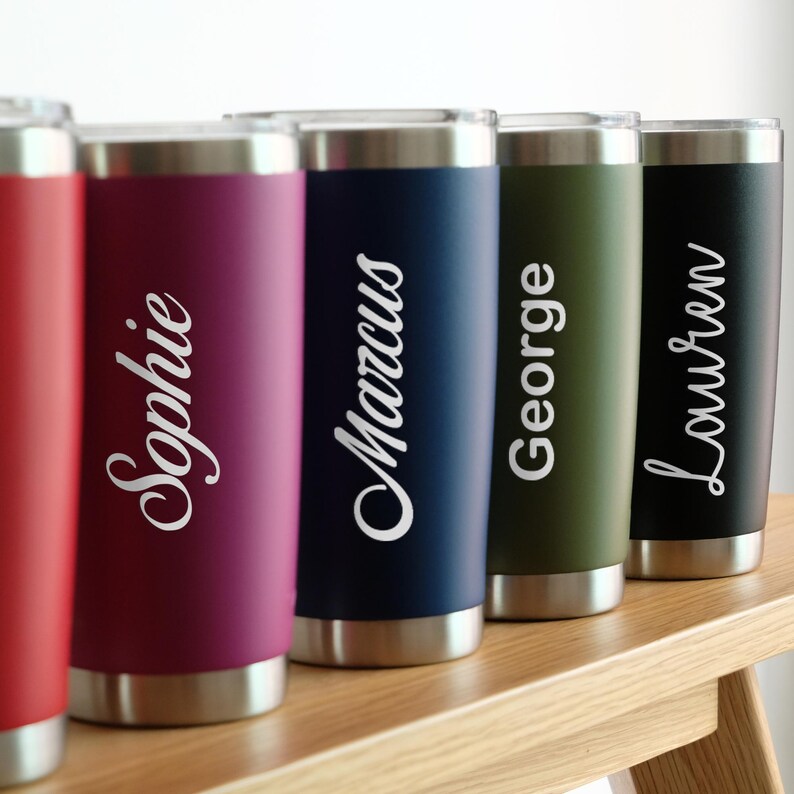 May include: Four stainless steel tumblers with personalized names: Sophie, Marcus, George, and Lauren. The tumblers are in various colors: red, blue, green, and black.