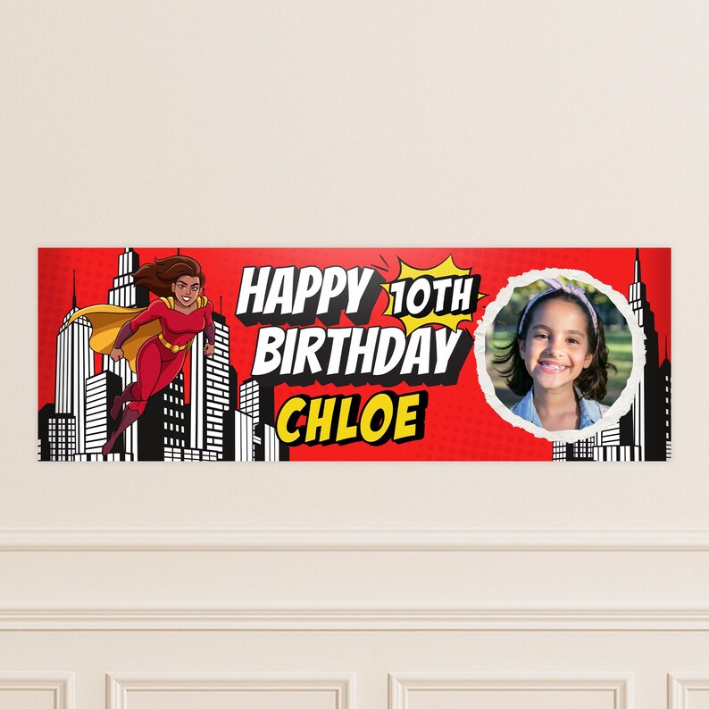Puede incluir: Una pancarta de cumplea&ntilde;os roja con tem&aacute;tica de superh&eacute;roes. La pancarta presenta una superhero&iacute;na de dibujos animados, un paisaje urbano y el texto "HAPPY 10TH BIRTHDAY CHLOE". Tambi&eacute;n se incluye una foto de una ni&ntilde;a sonriente.