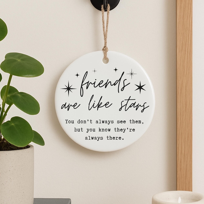 May include: A white, round ceramic wall hanging with the text "friends are like stars" in black script. The text below reads "You don't always see them, but you know they're always there." A decorative item for home decor.