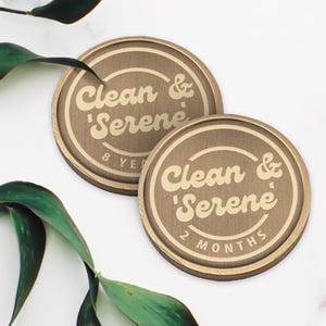 Pu&ograve; includere: Due gettoni rotondi in metallo color oro con il testo "Clean & 'Serene'" in un font retr&ograve;. Un gettone dice "8 Years" e l'altro "2 Months".