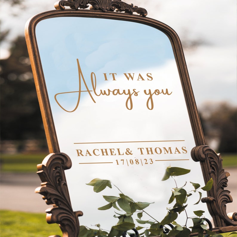 May include: A gold-framed mirror with the text "It was always you" and "Rachel & Thomas 17/08/23" written in gold lettering.