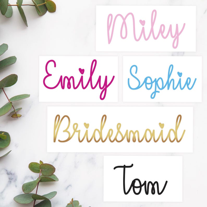 May include: Five white cards with different names written in colorful script. The names are Miley, Emily, Sophie, Bridesmaid, and Tom. Each name has a small heart symbol next to it.